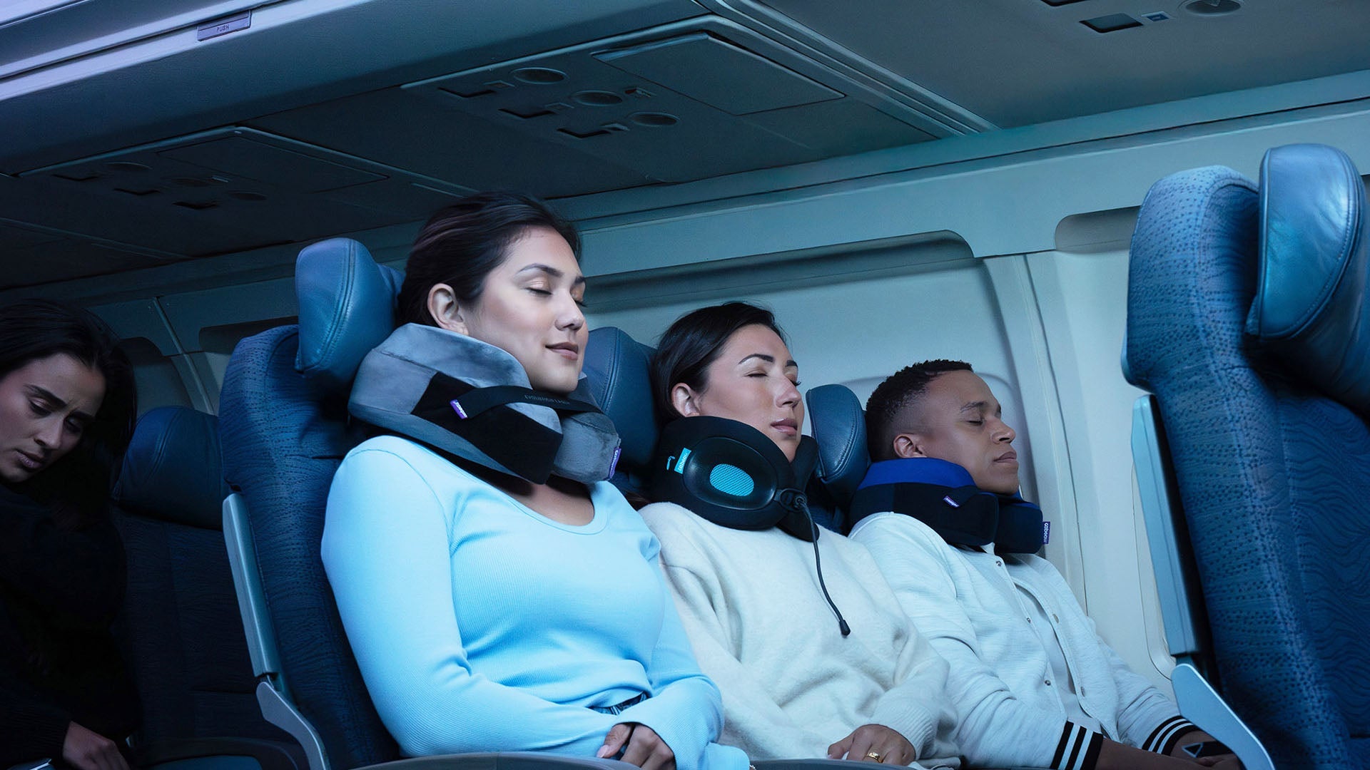 Three travelers sleeping on an airplane comfortably wearing neck pillows
