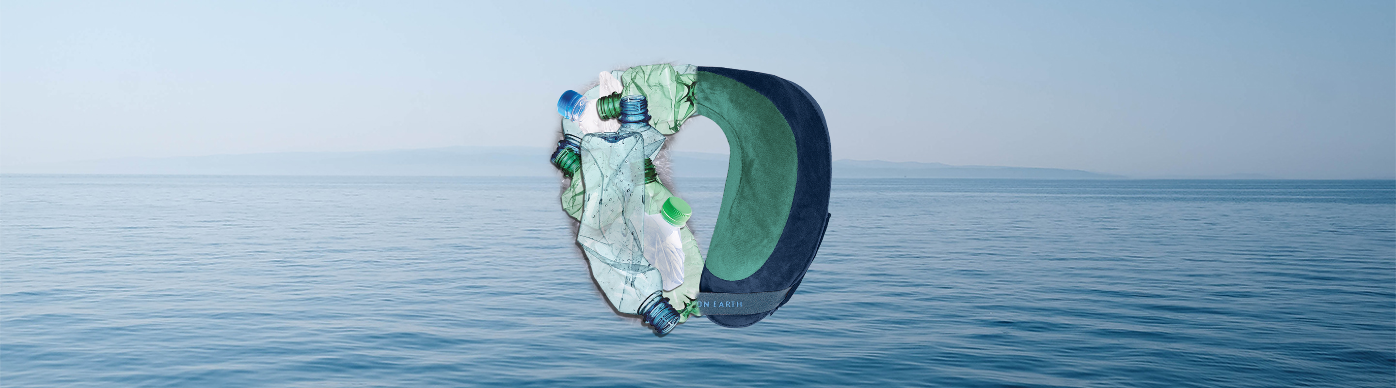 Half of an Evolution Earth Deluxe neck pillow with the other half pillow being made up of plastic bottle, against an ocean background
