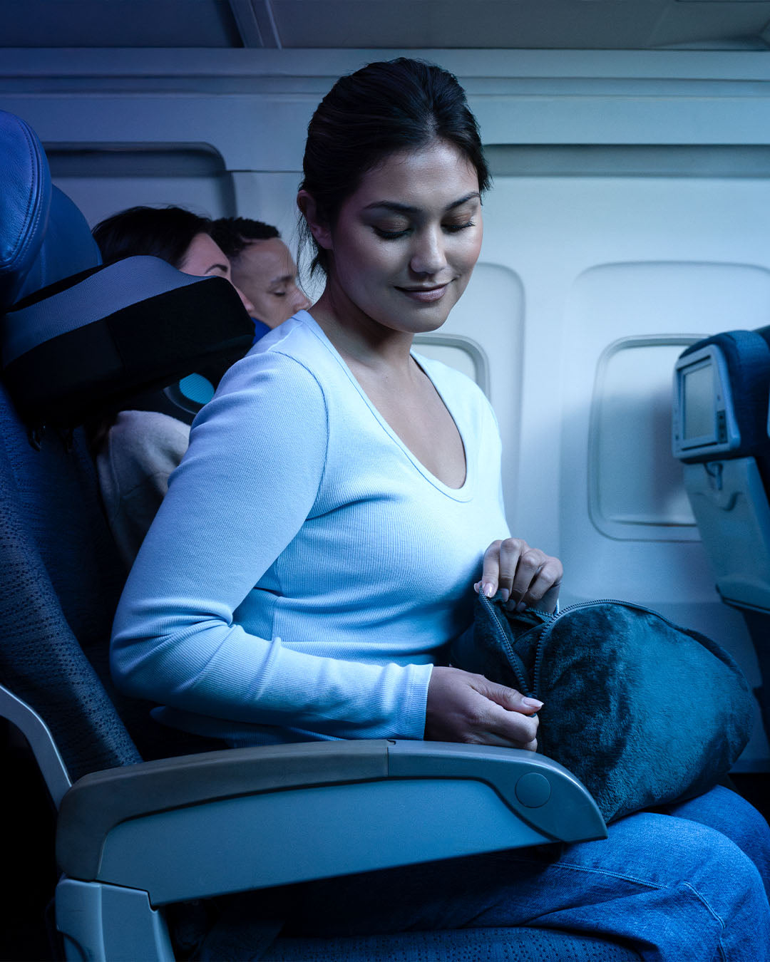 Woman sitting in an airplane seat with a blue light on her face