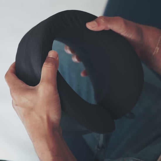 Squeezing neck pillow to show the softness of the memory foam